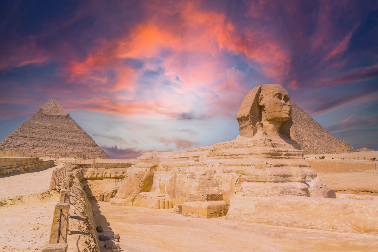 The Great Sphinx of Giza and in the background the Pyramids of Giza at sunset, the oldest funerary monument in the world. In the city of Cairo, Egypt