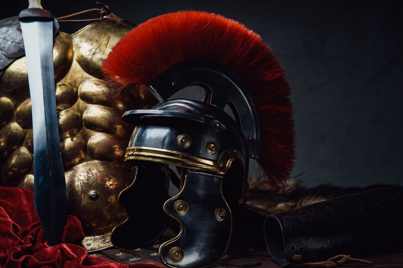 Closeup studio shot of ancient imperial legionary bronze armor and helmet with gladius.