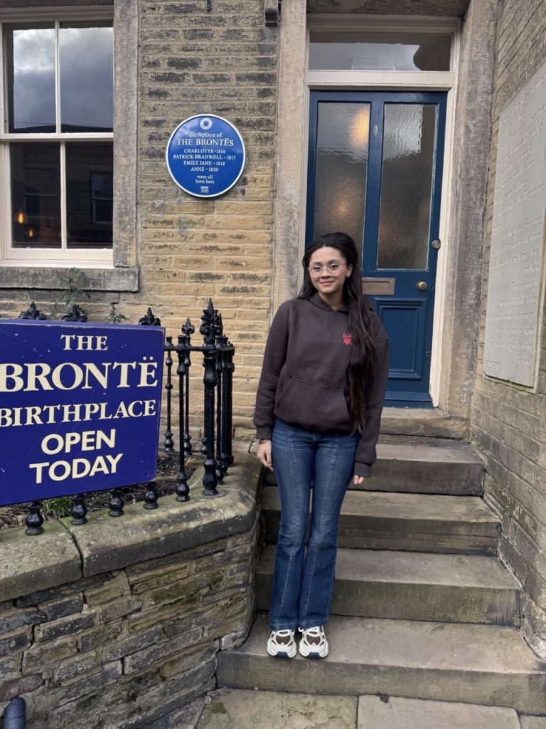 A student posing in front on the steps of the bronte birthplace
